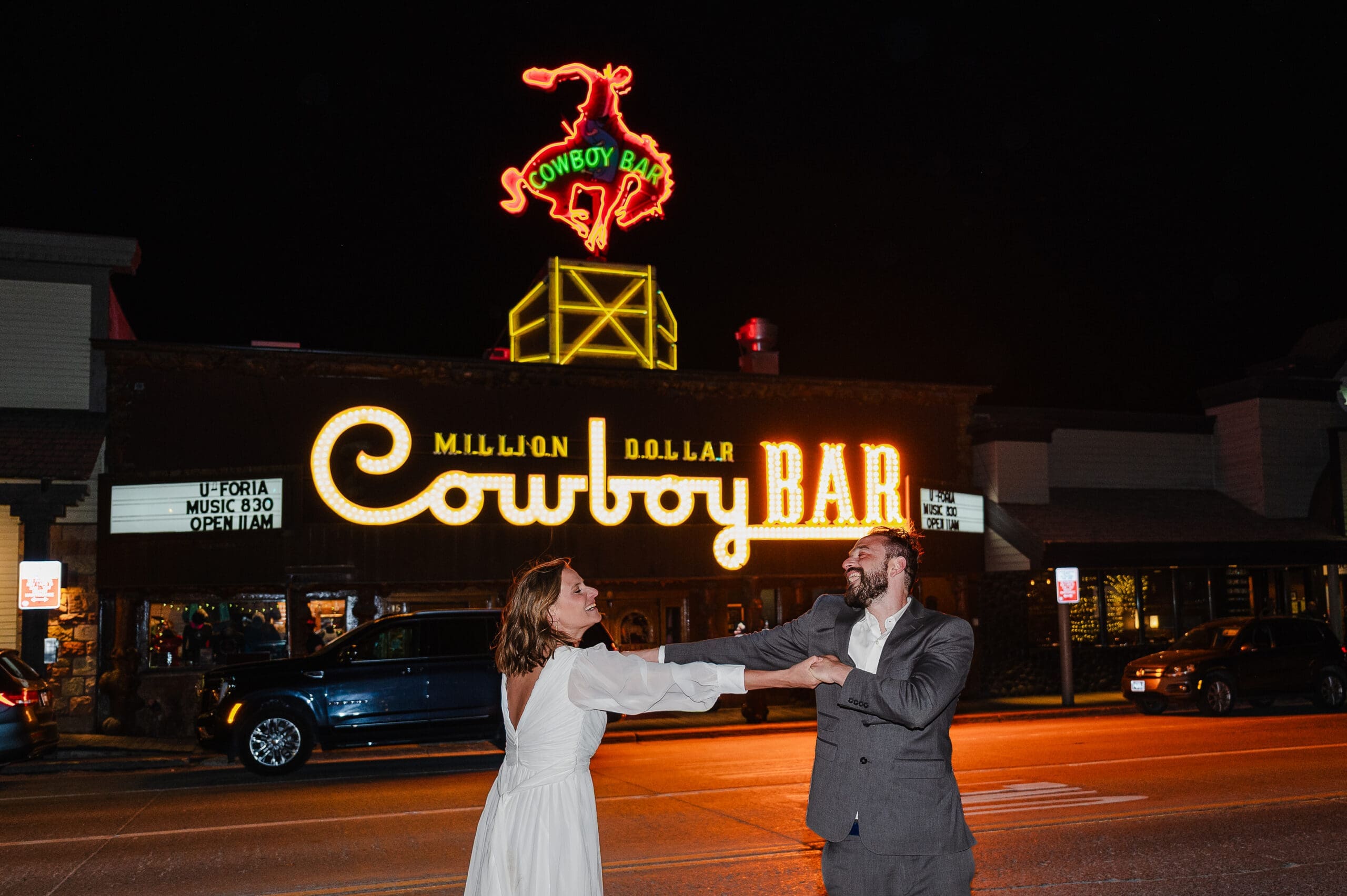 Bride and groom in their elopement attire dancing in the street at night in front of the Million Dollar Cowboy Bar to end their elopement day celebration.