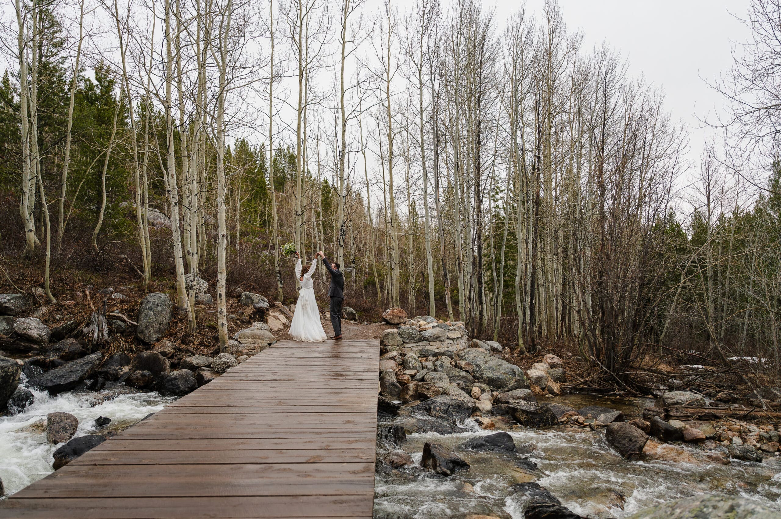 Elopement bride and groom walking across a wooden bridge on the hike to Taggart Lake for their vows.